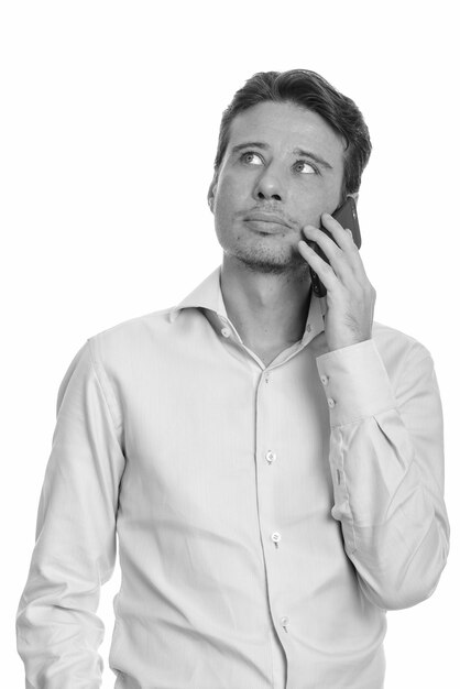 handsome businessman with beard stubble isolated against white wall in black and white