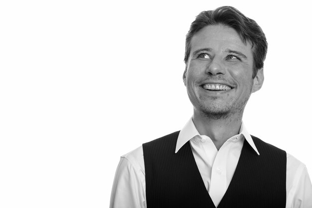 handsome businessman with beard stubble isolated against white wall in black and white