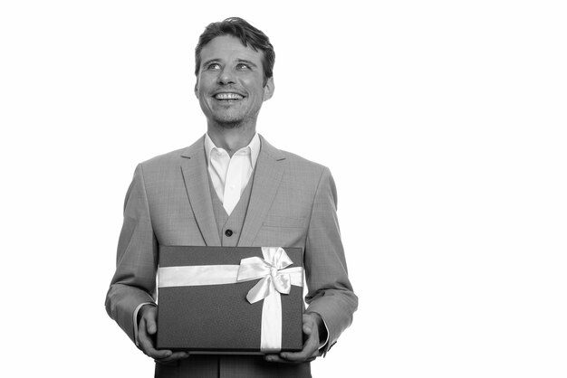  handsome businessman with beard stubble in suit isolated against white wall in black and white