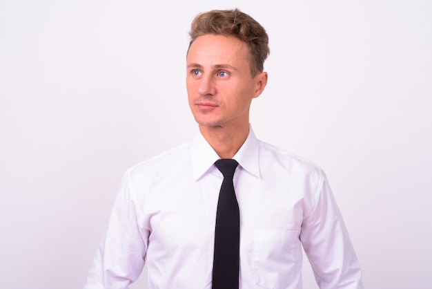  handsome businessman with blond curly hair against white wall