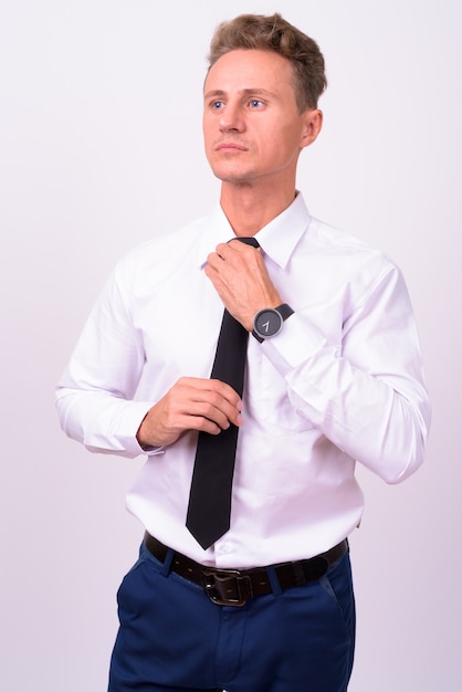  handsome businessman with blond curly hair against white wall