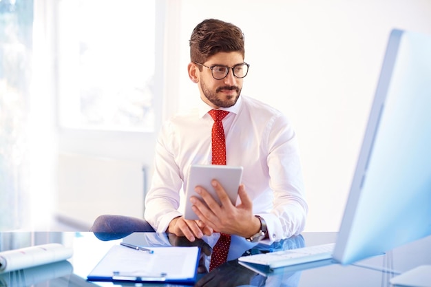 Handsome businessman working on digital tablet in the office