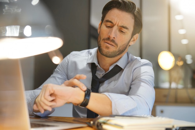 Foto uomo d'affari bello che lavora tardi alla notte in ufficio moderno