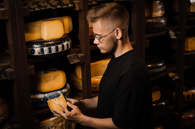 Handsome buyer in cheese shop looking at limited gouda cheese Snack tasty piece of cheese for appetizer