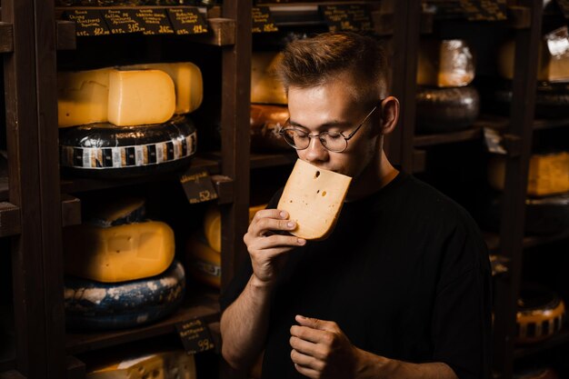 Handsome buyer in cheese shop sniff and enjoy limited gouda cheese Snack tasty piece of cheese for appetizer