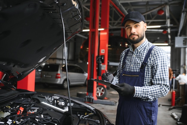 handsome car mechanic is posing in a car service