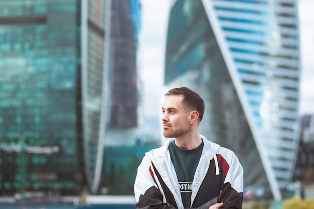 Handsome casual man in windbreaker standing on a skyscraper
view. sports style and business.