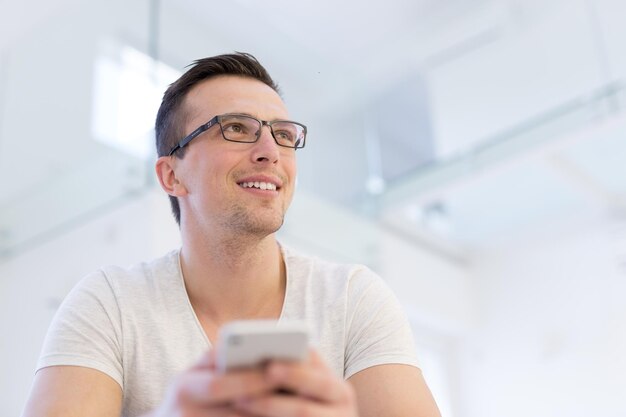 Handsome casual young man using a mobile phone at  home