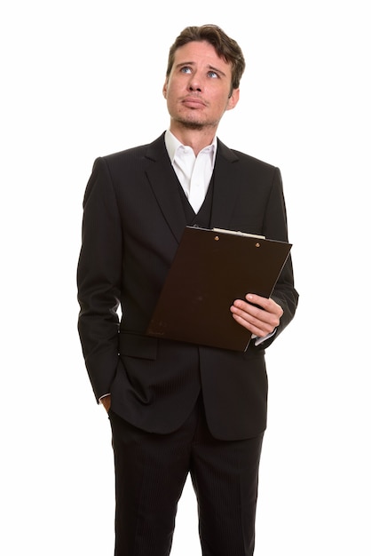 Handsome Caucasian businessman thinking while holding clipboard
