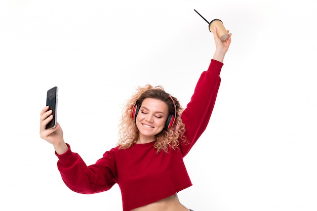 Handsome caucasian female with curly fair hair drinks coffe and do selfie