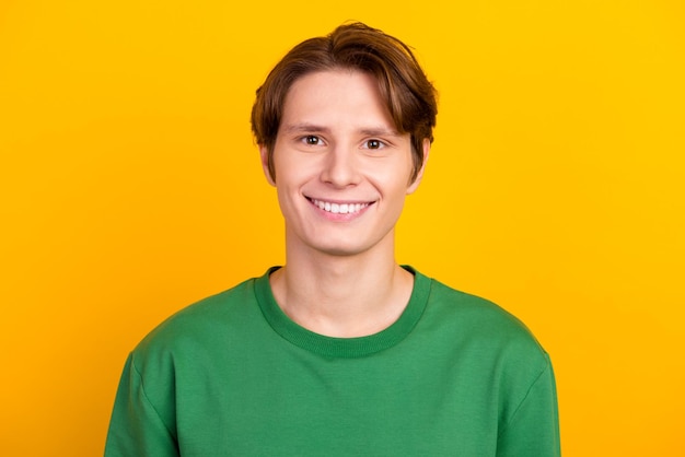 Handsome caucasian man smiling with white teeth looking confident at camera standing in green shirt on bright background