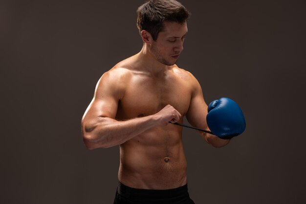 Handsome caucasian man wearing boxing gloves at his hands while posing over brown background. Stock photo