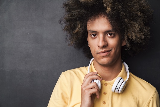  handsome caucasian man with afro hairstyle wearing headphones isolated over dark gray wall