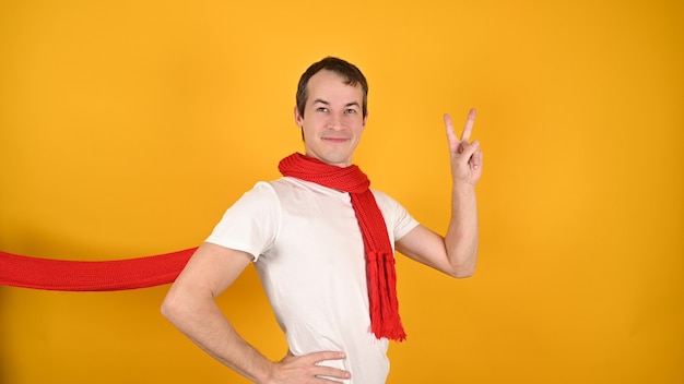 Handsome caucasian young man in red scarf looking to the camera showing fingers doing victory sign or number two.