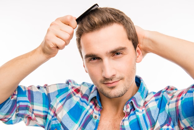 Handsome cheeky young man combing his hair