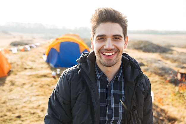 Handsome cheerful man camping outdoors