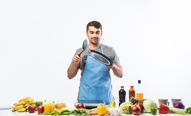Handsome cheerful smiling indian man preparing meal in the kitchen,  Healthy food, cooking concept.