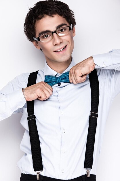 Foto bel giovane uomo allegro che indossa occhiali camicia con bretelle e la cravatta a farfalla sul collo persone emotive