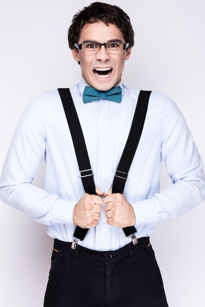 Photo handsome cheerful young man wearing glasses shirt with suspenders and the bow tie on his neck emotional people
