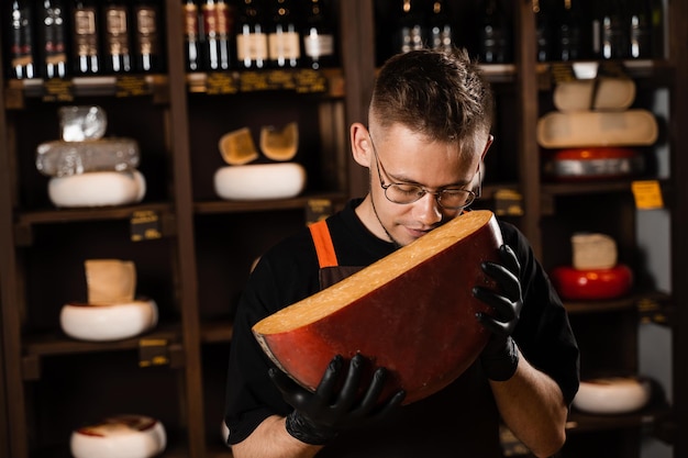 Handsome cheese sommelier holding and sniff limited gouda cheese Snack tasty piece of cheese for appetizer
