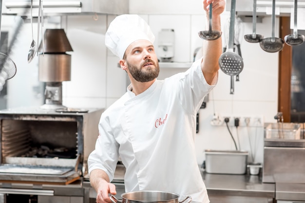 Handsome chef cook cooking food with pan and scoop at the restaurant kitchen