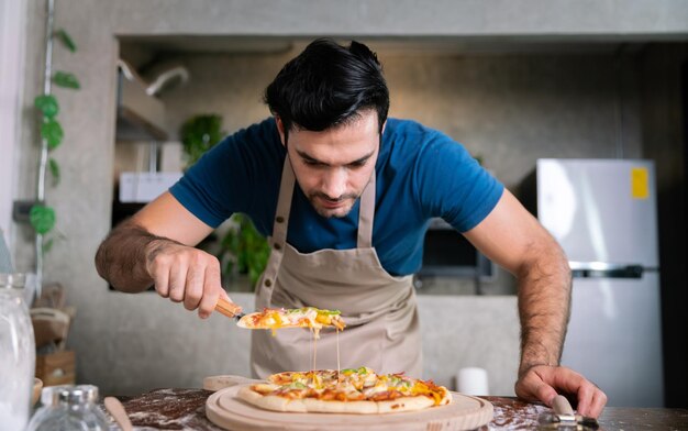 Красивый шеф-повар вырезал пиццу с моцареллой из плиты или духовки на обед в ресторане