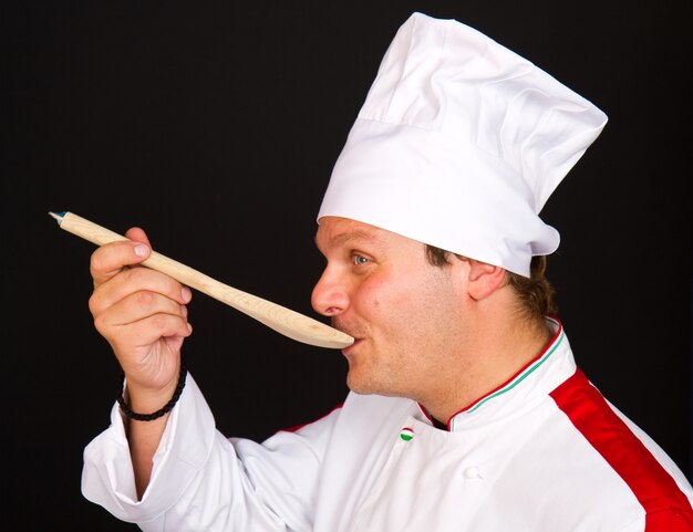 Handsome chef posing against black background