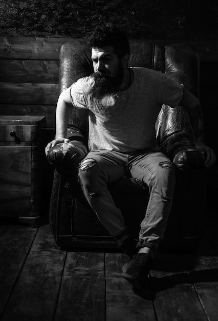 handsome confident bearded man sitting in luxury leather chair and looks grumpy stylish attractive