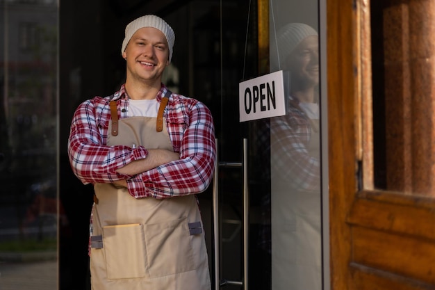 Handsome and confident cafe owner standing at the door Young man standing with his arms crossed looking at camera smiling