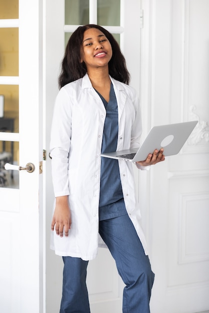 Красивая довольная афро-американская женщина-врач работает над телемедициной ноутбука