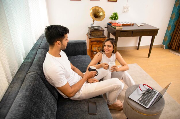 Photo handsome couple sitting together at home having coffee