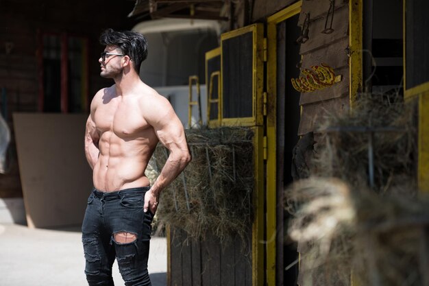 Handsome Cowboy Man Standing Strong and Posing at Ranch Outdoors Wearing Black Jeans