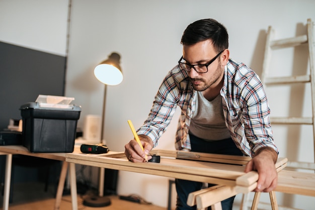 Handsome craftsman with pencil marking wooden frame.