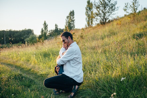 Photo handsome dad with his little cute son are having fun and playing on green grassy lawn