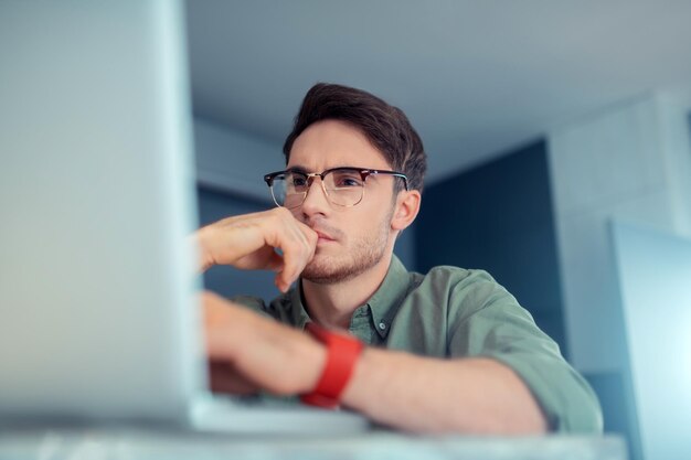 Bell'uomo d'affari dagli occhi scuri che si sente impegnato a lavorare sul laptop