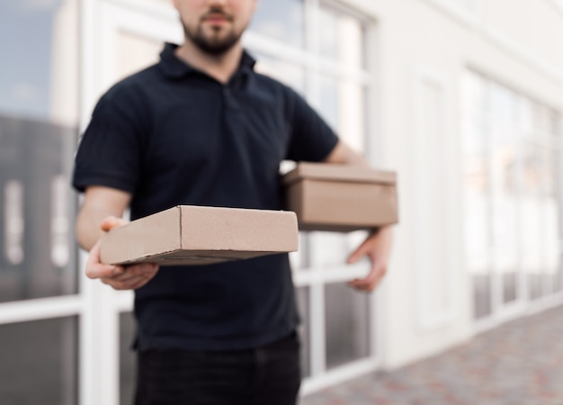 Photo handsome delivery man in black uniform with boxes