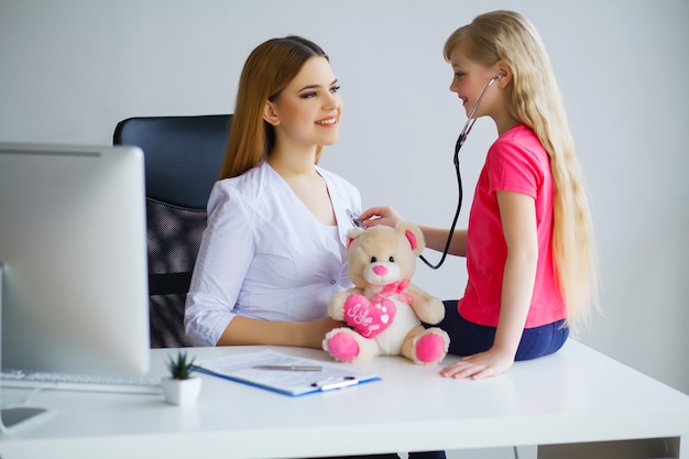 Handsome Doctor examining little girl with stethoscope