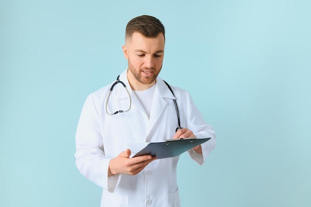 Handsome doctor man wearing coat and stethoscope over isolated blue background