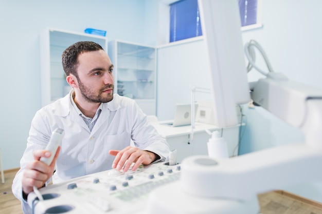 Handsome doctor using an ultrasound machine