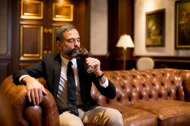 Handsome elegant businessman drinking red wine in bar