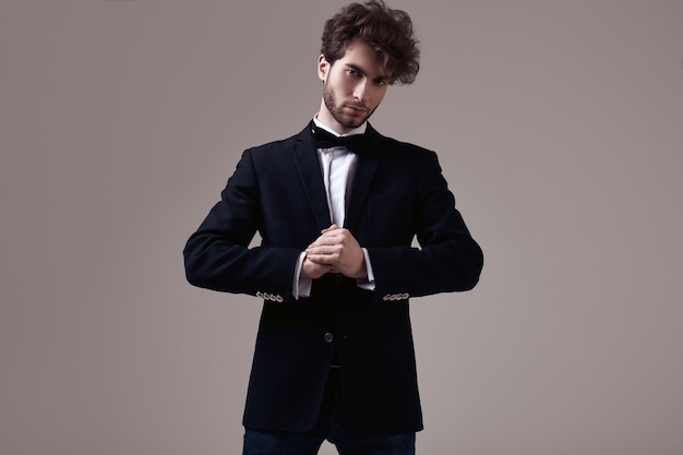 Handsome elegant man with curly hair wearing tuxedo