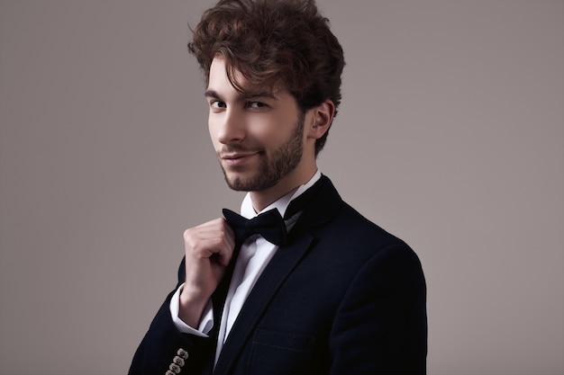 Uomo elegante bello con lo smoking da portare dei capelli ricci