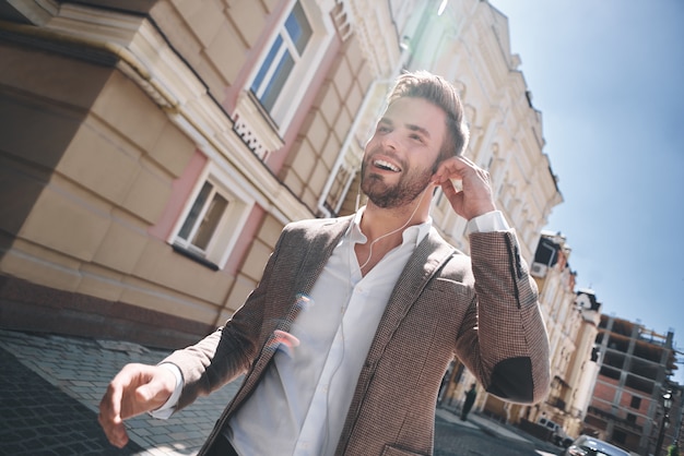 Handsome elegant young man in the street listening music from his phone