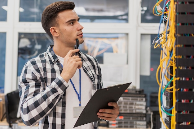 Photo handsome engineer with clipboard in server room