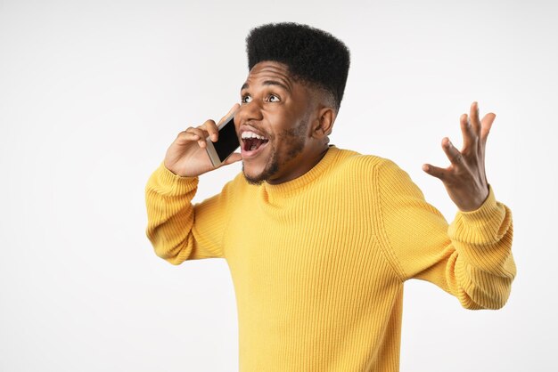 Photo handsome excited man expressing surprise on face and gesturing while speaking on telephone isolated over white background