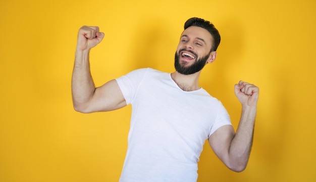 Handsome excited modern young bearded stylish man is posing with a wide toothy smile