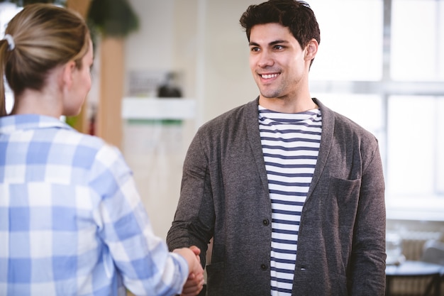 Handsome executive shaking hands with colleague at creative office