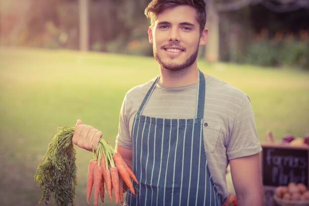 Handsome farmer holding carrots