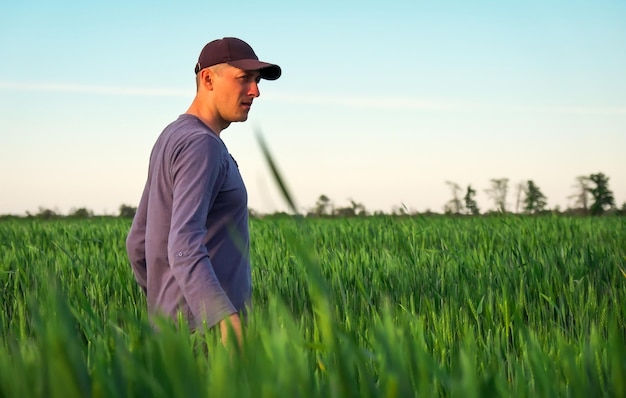 Handsome farmer Young man walking in green field Spring agriculture