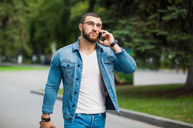 Photo handsome fashionable fit man talking over telephone on street. casual denim jeans wear.